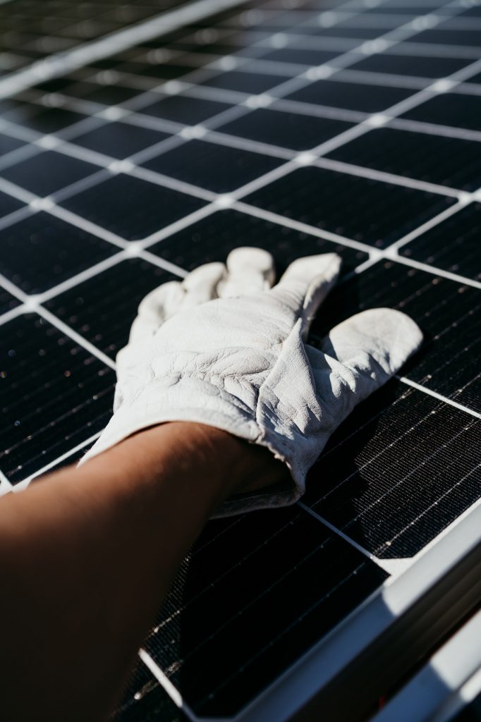 hand of Technician touching solar panels on house roof for self consumption energy. Renewable energy