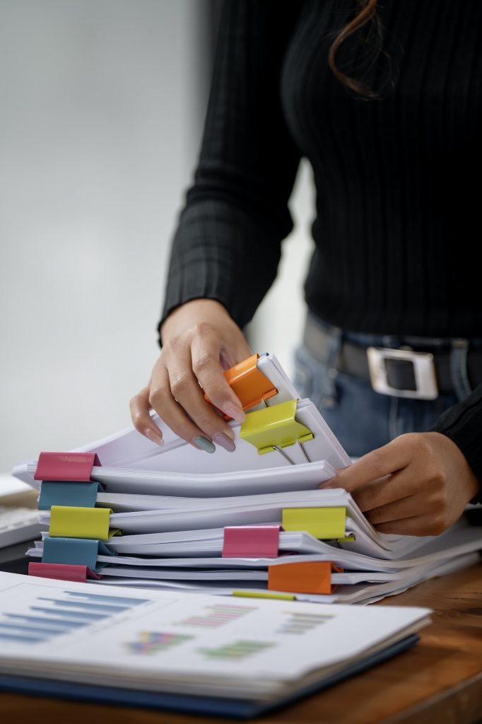 woman hands working on Stacks paper files for checking document achieves on folders paper at office.